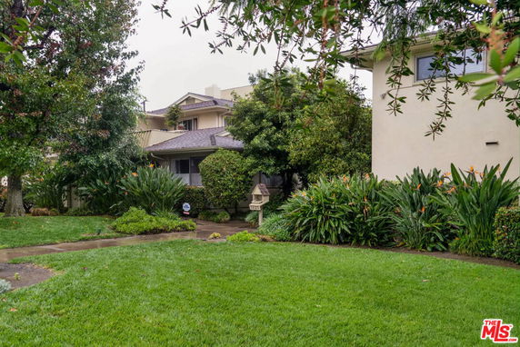 Front view of a two-story house surrounded by trees and shrubs.