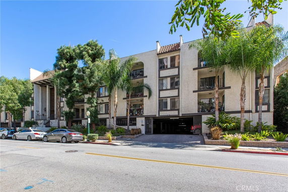 Front view of a multi-story apartment building with a parking area underneath.