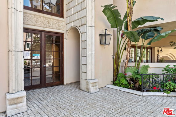 Front view of a building entrance with archways and decorative plants.