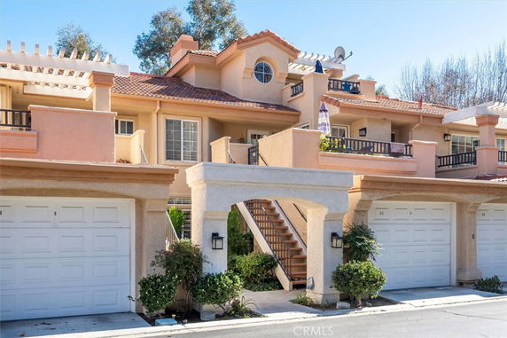 Front view of a multi-story residential building with garages and balcony.