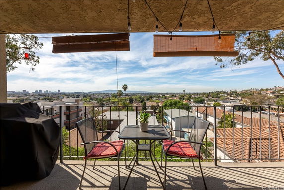 View from a balcony overlooking rooftops and distant city skyline.