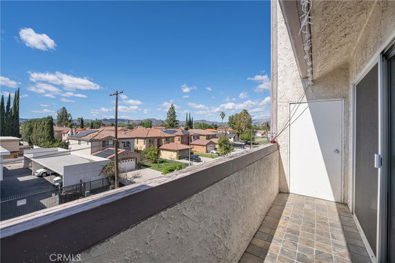 View from a balcony overlooking rooftops and distant mountains.