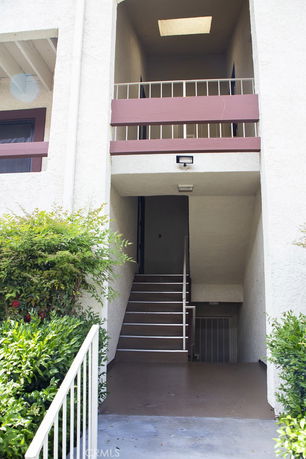 Front view of a multi-story building entrance with stairs and a landing.