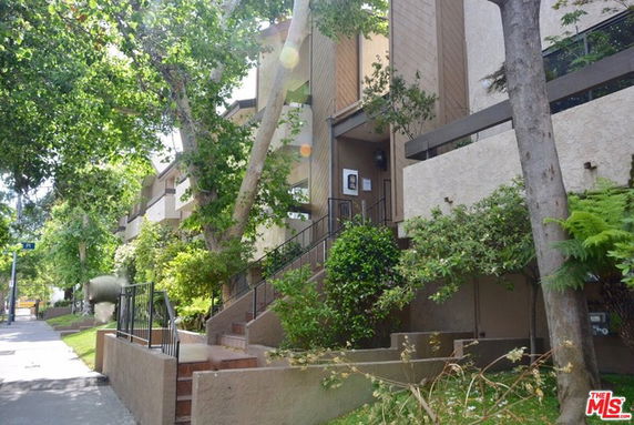 Front view of a multi-story building with a staircase and greenery.