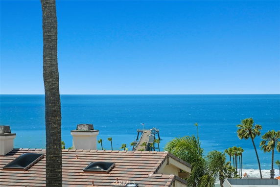 Rooftop with solar panes overlooking the ocean and palm trees.