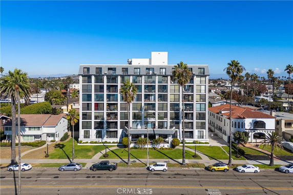 Front view of a multi-story apartment building with large windows and balconies.
