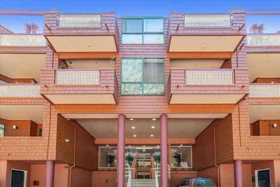 Front view of a multi-story building with balconies and large central windows.