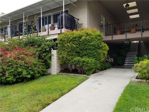 Front view of a two-story building with a covered balcony and a walkway leading to an entrance.