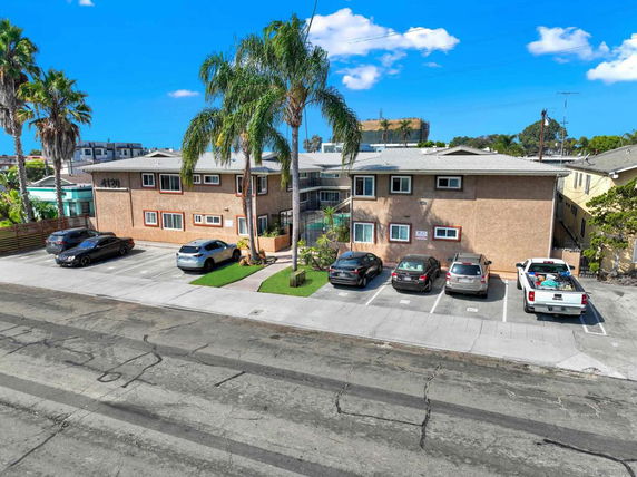 Front view of a two-story apartment building with parking spaces in front.