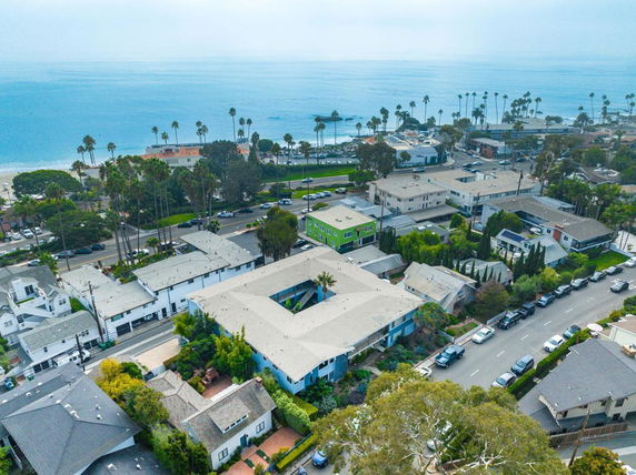Wide-angle view of a coastal residential area with multiple buildings and the ocean in the background.