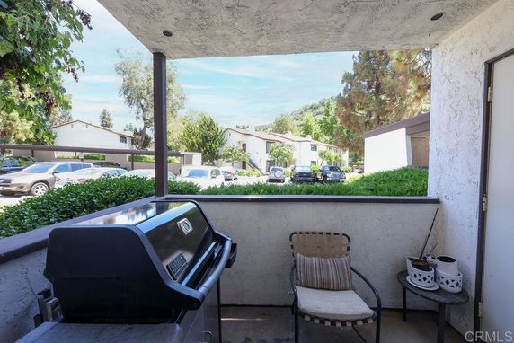 View from a patio showing parked cars and trees in a residential area.