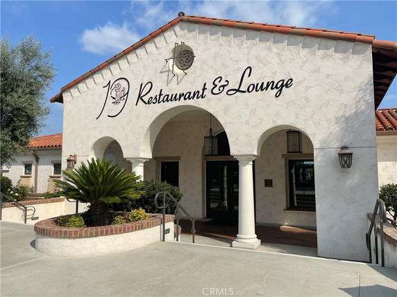 Front view of a building with the sign 'Restaurant & Lounge' featuring a stucco facade and tiled roof.