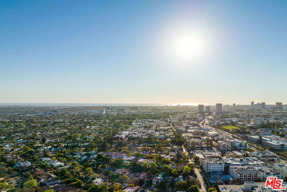 Panoramic view of a cityscape with buildings and green areas under a clear sky.