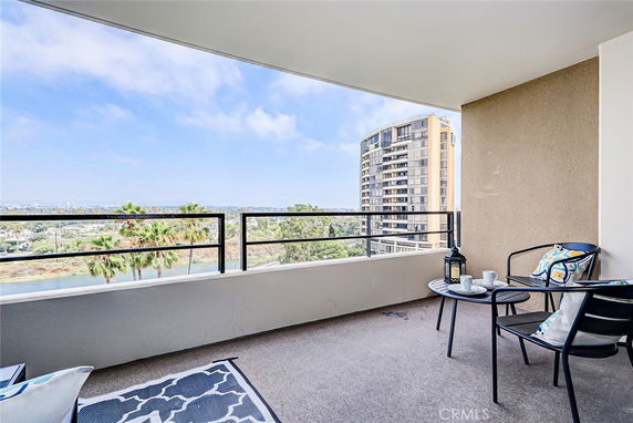 Balcony view with outdoor furniture overlooking a cityscape and a high-rise building.