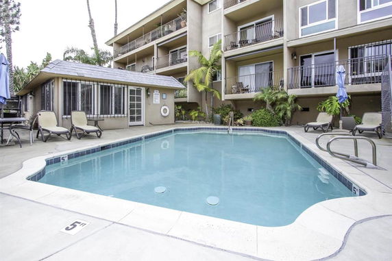 Outdoor swimming pool area with apartment building in the background.