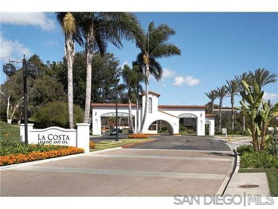 Front view of a resort entrance with arches and palm trees.