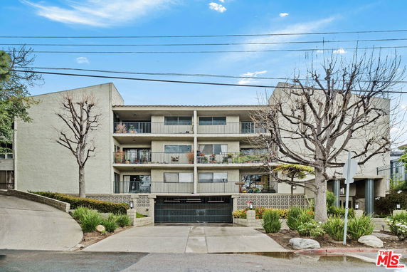 Front view of a multi-story apartment building with balconies and a central entrance.