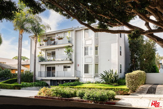 Front view of a multi-story residential building with balconies and white siding.