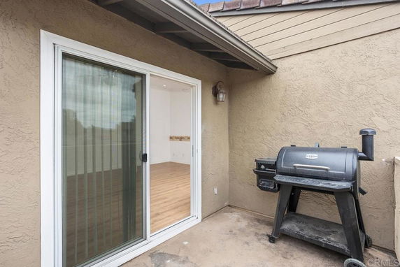 Small rooftop area with a portable grill and sliding glass doors leading to an interior space.