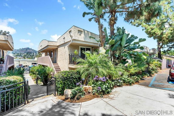 Front view of a multi-story building with external staircases and surrounding greenery.