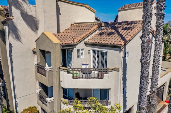 Front view of a multi-story residential building with balconies and tiled roof.