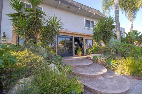Front view of a two-story house with a stone pathway and plants.