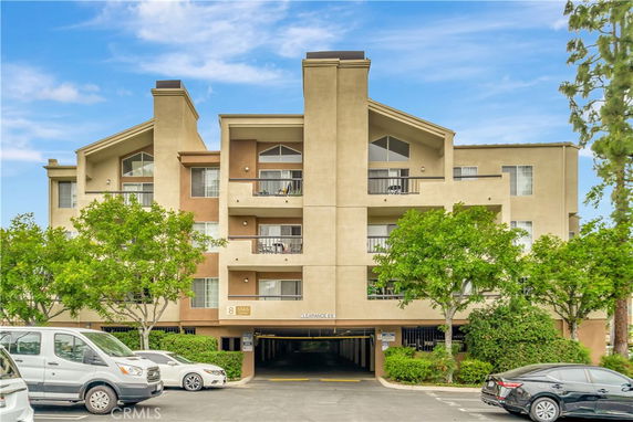 Front view of a multi-story apartment building with balconies and parking area.