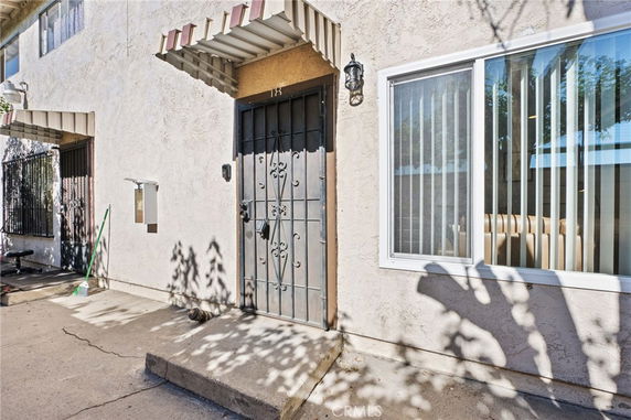 Front view of a building entrance with a metal door and window with blinds.