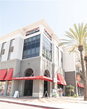 Front view of a commercial building with red awnings and large windows.