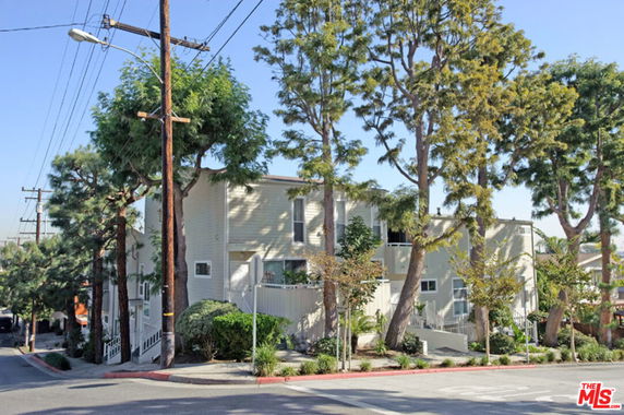 Front view of a multi-story residential building with trees around it.