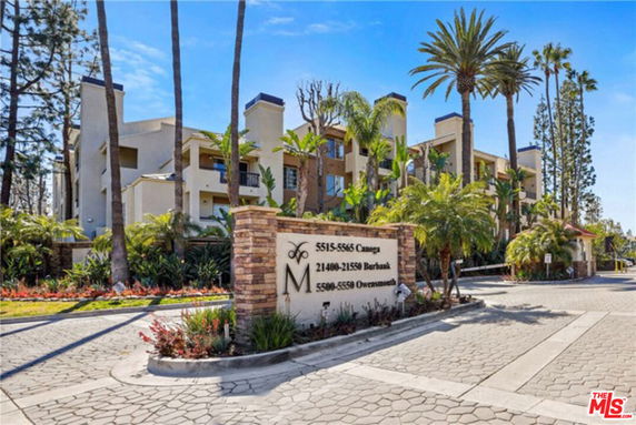 Front view of a multi-story residential complex with palm trees and greenery.