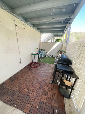 Covered outdoor area with wooden flooring and a barbecue grill.