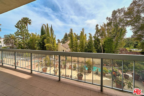Panoramic view from a balcony overlooking a garden and swimming pool.