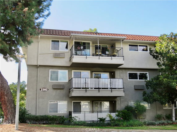 Front view of a three-story residential building with multiple balconies.