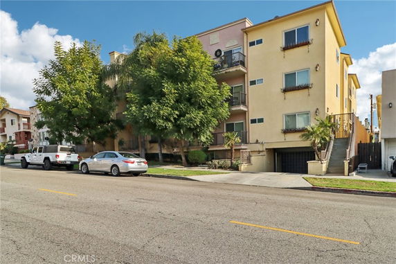 Front view of a multi-story apartment building with balconies and garage entry.