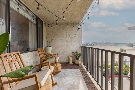 Balcony with rocking chairs overlooking a waterfront area.