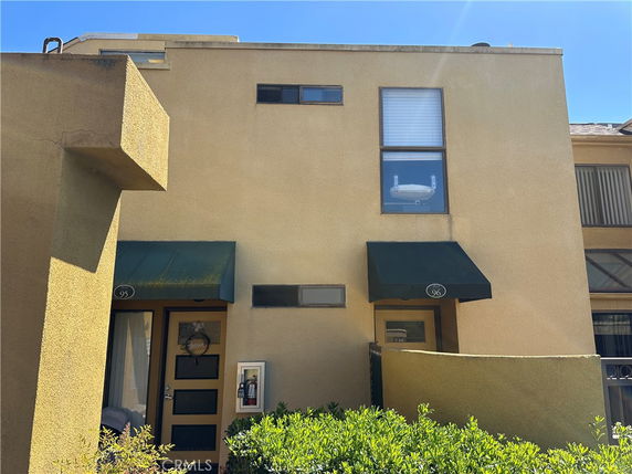 Front view of a two-story building with green awnings over doorways.