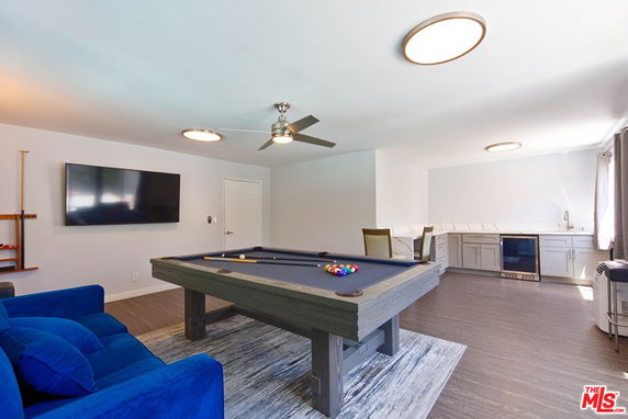Recreation room with a pool table, seating area, and a small kitchen setup.