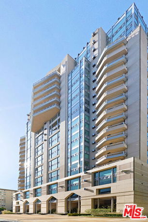 Front view of a tall modern apartment building with multiple balconies.