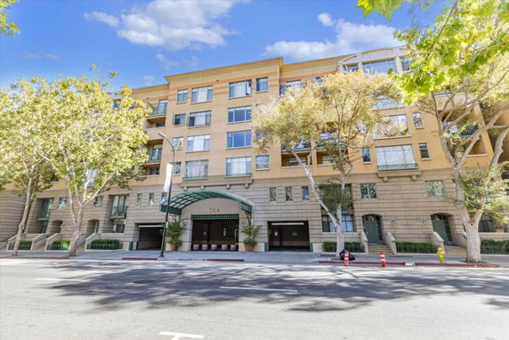 Front view of a multi-story residential building with large windows and an arched entrance.