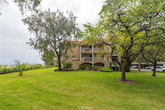 Front view of a multi-story building with balconies and a green lawn.
