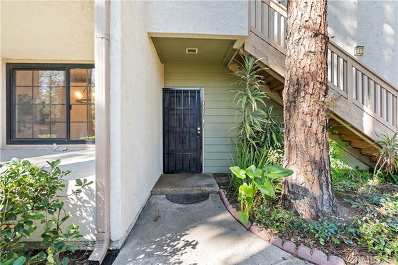 Front view of an entrance to a residential building with stairs and plants.