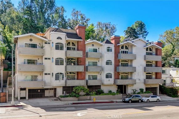 Front view of a multi-story apartment building with balconies and a brick facade.