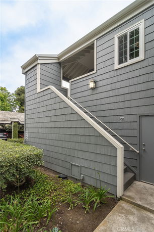 Side view of a two-story building with gray siding and an external staircase.