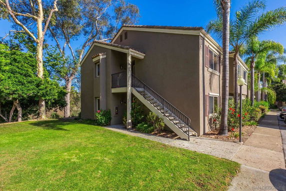 Front view of a two-story building with an external staircase and landscaped surroundings.