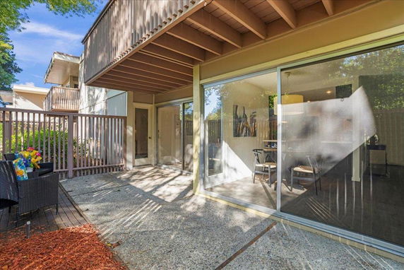 Exterior view of a house with sliding glass doors and a balcony above.
