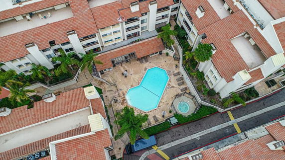 Aerial view of a central swimming pool surrounded by a residential building with red-tiled roofs.
