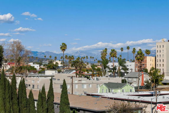 Panoramic view of urban area with buildings, palm trees, and distant mountains.