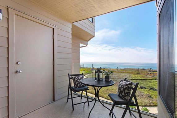 Patio with a small table and chairs overlooking a scenic ocean view.
