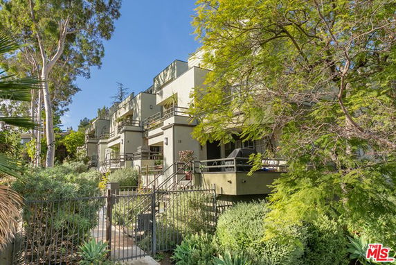Front view of a multi-story residential building with balconies and a gated entrance.